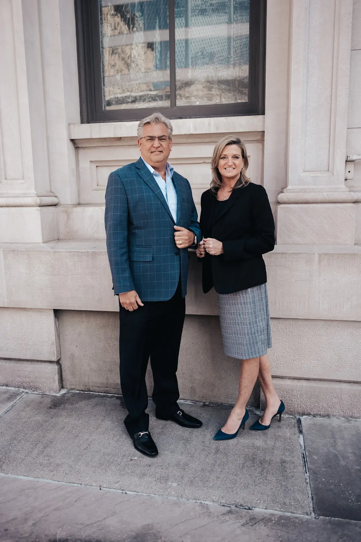 Steve and Melissa Fultz in business attire outside a stone office building
