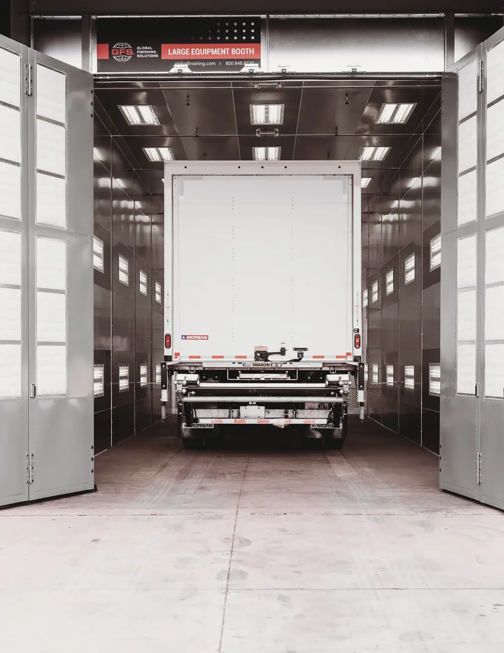 A white truck inside the open paint booth