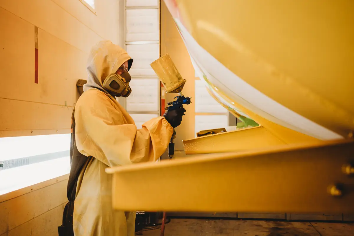 A painter in a respirator working in the Post Onsite paint booth